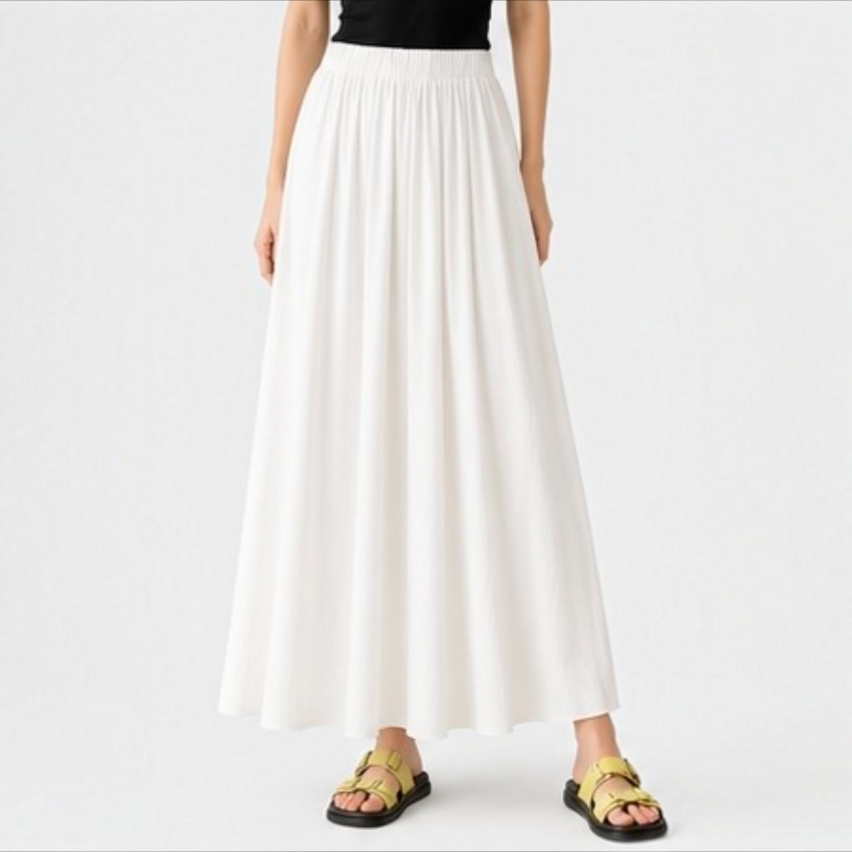 Model wearing the creamy white Joyjocey High-Waist Pleated A-Line Skirt with a flowy maxi-length silhouette, front view.