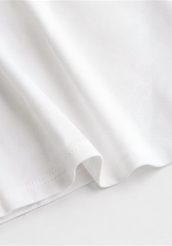Close-up of the soft white cotton fabric and finished hem on the Joyjocey Side-Tie Cotton Top.