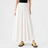 Model wearing the creamy white Joyjocey High-Waist Pleated A-Line Skirt with a flowy maxi-length silhouette, front view.
