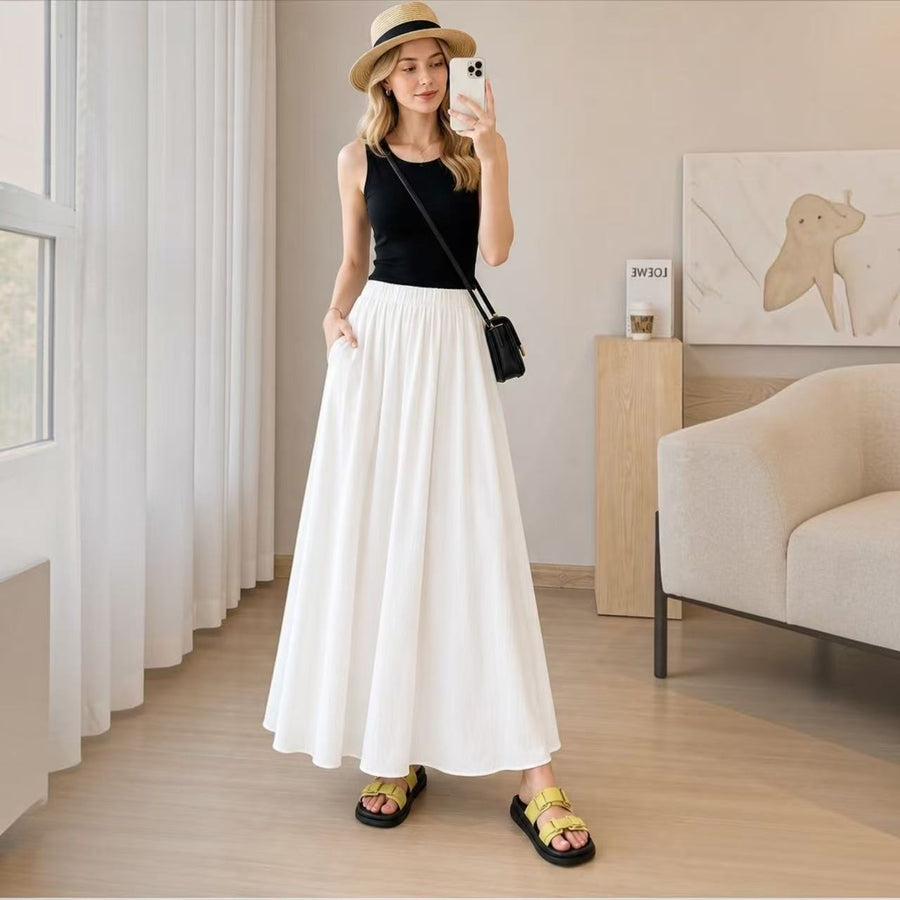 Model styling the creamy white Joyjocey High-Waist Pleated A-Line Skirt with a black tank top, sun hat and sandals.