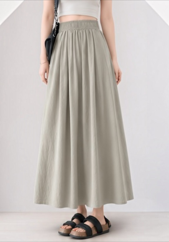 Model wearing the grey Joyjocey High-Waist Pleated A-Line Skirt with an elastic waistband and flowy silhouette, front view.