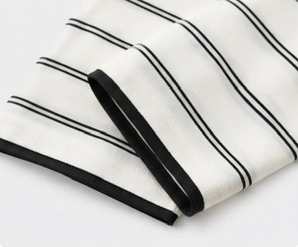 Black-trimmed cuff and horizontal stripe detail on the white Joyjocey Relaxed Striped Long-Sleeve Top.