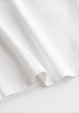 Close-up of the soft white cotton fabric and finished hem on the Joyjocey Side-Tie Cotton Top.