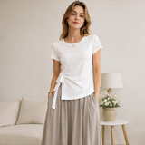 Model wearing the Joyjocey Side-Tie Cotton Top in white with an asymmetrical hem and adjustable waist tie, front view.