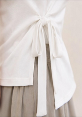 Adjustable white waist tie and asymmetrical side slit detail on the Joyjocey Side-Tie Cotton Top.